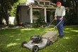 Portrait of elderly man mowing lawn