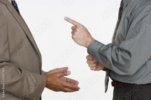 Photo: Mid section of two businessmen facing each other with hands gesturing Mid section of two businessmen facing each other with hands gesturing