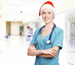 Smiling female medical doctor wearing red hat in a hall of a hos