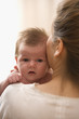 Rear view of mother holding baby on her shoulder