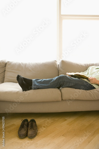 Photo: Young man relaxing on the couch without shoes Young man relaxing on the couch without shoes