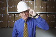Businessman wearing hard hat and saluting in warehouse