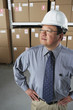 Middle-aged Asian businessman wearing hard hat in warehouse