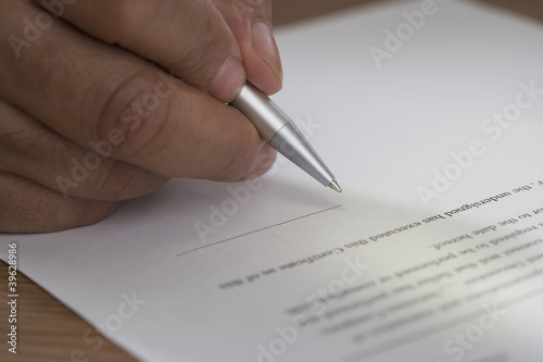 Photo: Close up of man signing document Close up of man signing document