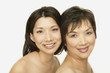 Studio shot of Asian mother and adult daughter smiling