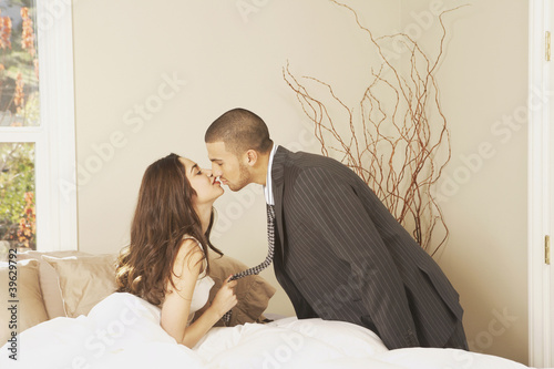 Photo: Hispanic man wearing a suit kissing Hispanic woman sitting in bed Hispanic man wearing a suit kissing Hispanic woman sitting in bed