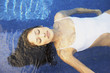 Hispanic woman floating in pool