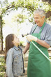 Hispanic grandfather and granddaughter playing with hose