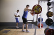 Male personal trainer with male client lifting weights