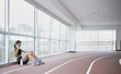 Woman using cell phone on side of indoor track