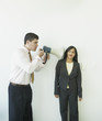 Businessman with megaphone yelling at businesswoman