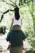 Father holding daughter on shoulders in woods