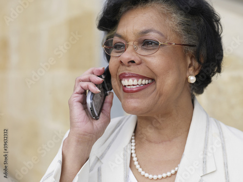 Photo: Senior African businesswoman using cell phone outdoors Senior African businesswoman using cell phone outdoors