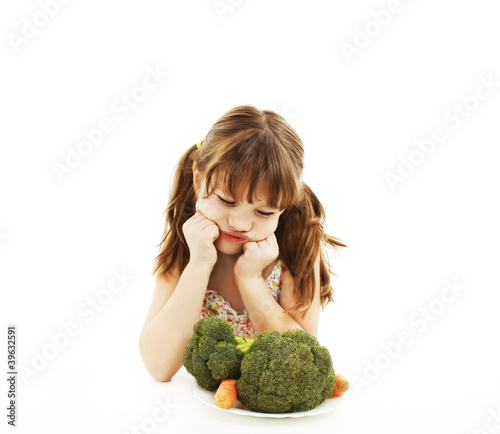 Photo: A cute little girl looks in disgust at her plate of vegetables A cute little girl looks in disgust at her plate of vegetables