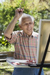 Senior man painting with easel outdoors