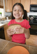 Hispanic girl eating sandwich in kitchen
