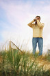 Man standing on sand dune taking photograph