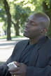 African man listening to mp.3 player in park