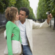 African couple taking own photograph in park