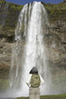 Woman wearing backpack and looking at waterfall