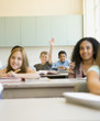 Students smiling at desks in classroom