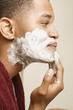 African man applying shaving cream to face