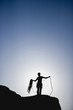 Silhouette of rock climber with rope on mountain
