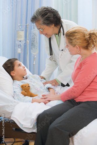 Photo: Senior female doctor talking to girl in hospital bed Senior female doctor talking to girl in hospital bed