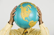 Native American businessman holding globe in front of face