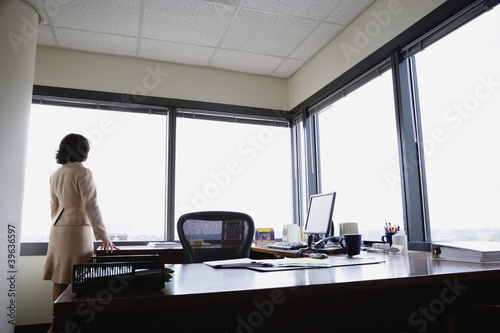 Photo: Rear view of businesswoman looking out window Rear view of businesswoman looking out window
