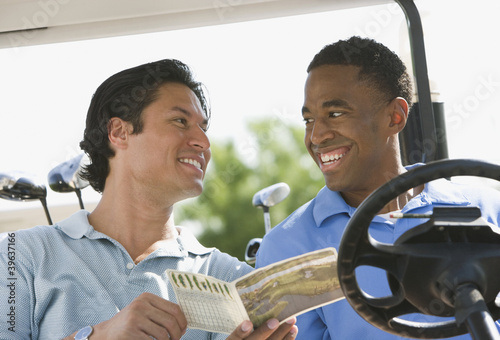 Photo: Two men smiling at each other in golf cart Two men smiling at each other in golf cart