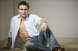 Man sitting on floor with shirt unbuttoned