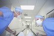 Male and female doctors wheeling gurney down corridor