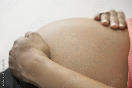 Photo: Close up of pregnant African woman's hands on bare belly Close up of pregnant African woman's hands on bare belly