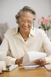 Senior African woman paying bills at table