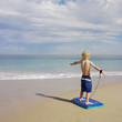 Boy standing on boogie board at beach