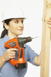Hispanic female construction worker using drill