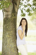 Portrait of Hispanic woman leaning against tree