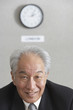 Senior Asian businessman under wall clock