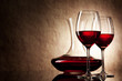 decanter with red wine and glass on a old stone background