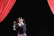 Hispanic girl holding trophy on stage