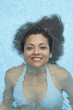 Hispanic woman floating in swimming pool
