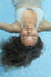 Hispanic woman floating in swimming pool