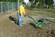 Middle age man with a rototiller in the garden
