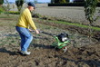 Middle age man with a rototiller in the garden