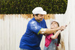 Hispanic father and daughter painting fence