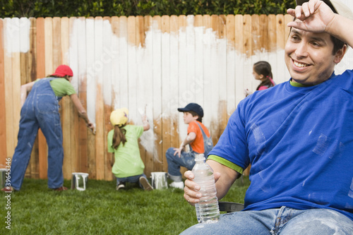 Photo: Mixed Race family painting fence Mixed Race family painting fence