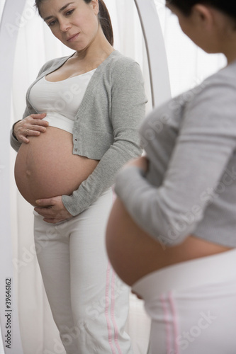 Photo: Pregnant Hispanic woman looking in mirror Pregnant Hispanic woman looking in mirror