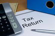Tax return papers lying next to folder and calculator