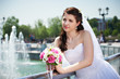 Happy bride about fountain with bouquet